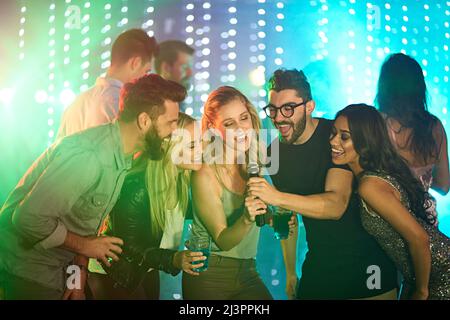 Es gibt einen Superstar in uns allen. Aufnahme einer Gruppe von Freunden, die auf einer Party Karaoke singen. Stockfoto