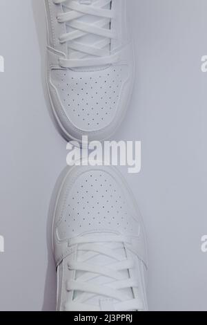 Draufsicht auf zwei weiße Sneakers auf weißem Hintergrund - vertikal Stockfoto