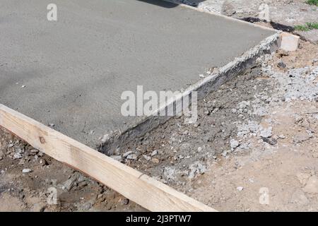 Fundamentschalung mit Zement gefüllt. Der Prozess des Baus des blinden Bereichs des Grundbaus des Hauses. Betonfundament für altes Haus. Stockfoto