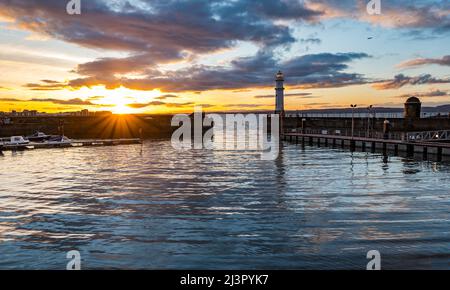 Edinburgh, Schottland, Großbritannien, 9.. April 2022. UK Wetter: Sonnenuntergang am Newhaven Hafen: Die Sonne geht an einem kühlen, aber sonnigen Frühlingstag über dem Firth of Forth und dem Newhaven Leuchtturm unter. Stockfoto