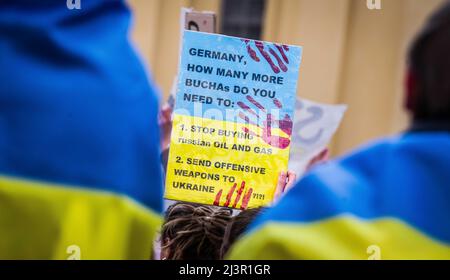 München, Bayern, Deutschland. 9. April 2022. Deutschland, ein Demonstrator in München, hält ein Zeichen, in dem die deutsche Regierung aufgefordert wird, der Ukraine mehr zu helfen, nachdem enthüllt wurde, dass Merkel angeblich die Verteidigungsunterstützung für die Ukraine direkt behindert hat, während sie eine Putin-freundliche Politik verfolgt, die sich als strategischer Exploit für Russland erweist. Nach dem jüngsten Kapitel der Gräueltaten, die das russische Militär in Bucha begangen hat, und dem Raketenangriff auf den Bahnhof Kramatorsk, standen Ukrainer, ukrainische Flüchtlinge, Deutsche und Menschen aus der ganzen Welt zusammen, um einen Stopp der russischen Militärs zu fordern Stockfoto