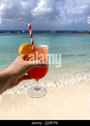 Ein tropisches alkoholisches Getränk „Aruba Ariba“ an einem sonnigen Aruban-Strand. Stockfoto