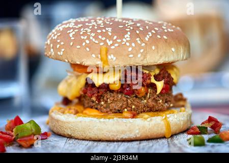 100% Vegetarischer Cheeseburger mit verschiedenen Gemüsesorten auf einem Holztisch Stockfoto