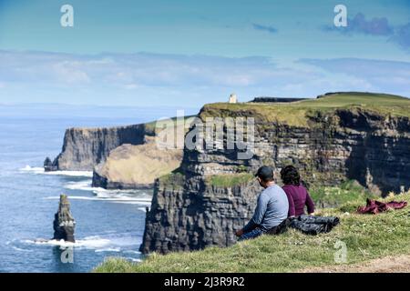 Ein Paar bewundern die Aussicht auf die Cliffs of Moher, die Meeresklippen am südwestlichen Rand der Region Burren in der Grafschaft Clare, Irland Stockfoto