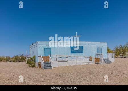 Eine blaue Anhängerkirche in Slab City, Kalifornien, mit einem weißen Holzkreuz oben und mit Treppen an beiden Enden. Die Kirche ist über eine lange ADA zugänglich Stockfoto