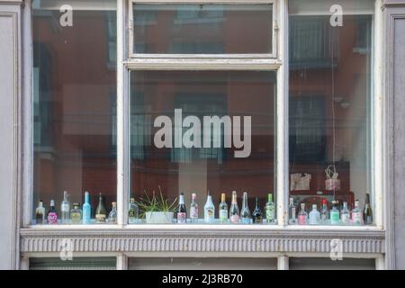 Studentenunterkunft, Alkoholflaschen aufgereiht in einem Fenster Stockfoto