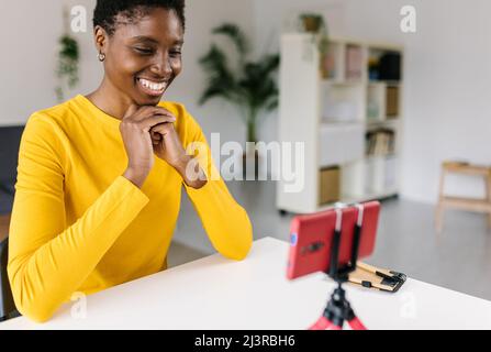 Glückliche junge afrikanische Frau, die mit dem Smartphone Videos überträgt und aufnimmt Stockfoto