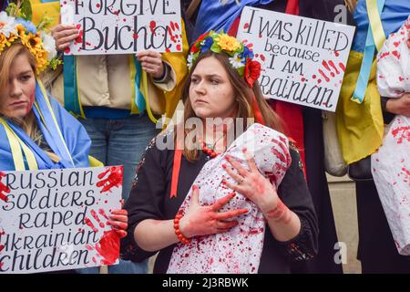 London, England, Großbritannien. 9. April 2022. Demonstranten inszenierten einen massiven "Einmarsch" und hielten "Babys" und Schilder fest, die mit gefälschtem Blut bedeckt waren, um gegen das Massaker in der Stadt Bucha und die Gräueltaten zu protestieren, die angeblich von russischen Truppen in der Ukraine begangen wurden. (Bild: © Vuk Valcic/ZUMA Press Wire) Stockfoto