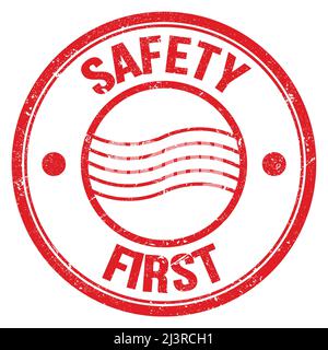 SICHERHEIT ERSTER Text auf rotem runden Briefmarkenschild geschrieben Stockfoto