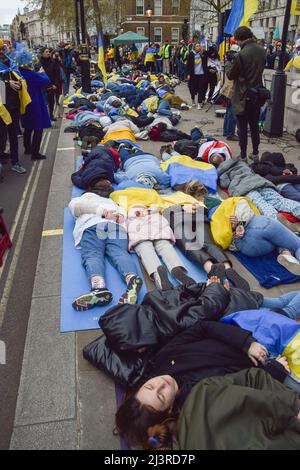 London, Großbritannien. 9.. April 2022. Demonstranten liegen auf der Straße. Demonstranten inszenierten einen massiven "Einmarsch" und hielten Schilder mit gefälschtem Blut bedeckt, um gegen das Massaker in der Stadt Bucha und die Gräueltaten zu protestieren, die angeblich von russischen Truppen in der Ukraine begangen wurden. Kredit: Vuk Valcic/Alamy Live Nachrichten Stockfoto