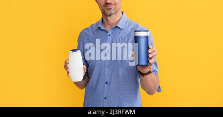 Mann verwenden Duschgel. Kerl wählen Shampoo oder Haarspülung. Tägliche Gewohnheiten und persönliche Pflege. Stockfoto