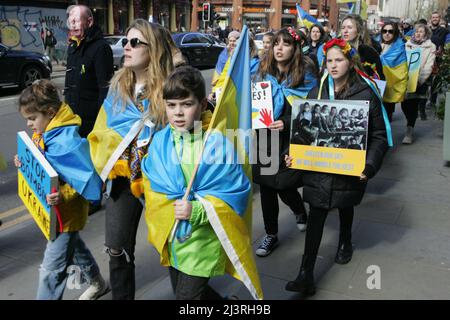 Ukrainische Demonstranten in Manchester marschieren, während sie während der Demonstration Plakate halten. Rund 200 Mitglieder der ukrainischen Gemeinde in Manchester sowie Ukrainer des Kulturzentrums „Dnipro“ marschierten durch das Stadtzentrum. Sie forderten ein Ende der Feindseligkeiten, der Invasion und des Mordes an Zivilisten, die gegen sie verübt wurden, seit Russland im Februar dieses Jahres ohne Provokation in die Ukraine einmarschierte. Viele ukrainische Kinder waren anwesend, als sie plakate hielten, auf denen die Gräueltaten der russischen Armee in Städten wie Bucha und Kramatorsk hervorgehoben wurden. Stockfoto