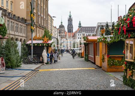 Dresdner Striezelmarkt mit kleinen Holzhäusern am berühmten Weihnachtsmarkt in Sachsen. Blick entlang der alten Straße mit einem alten Turm in der Skyline. Stockfoto