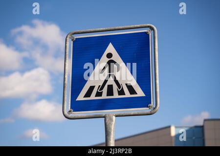 Fußgängerüberweg Verkehrsschild in Deutschland. Person, die auf Zebrastreifen auf einem blauen quadratischen Straßenschild läuft. Regeln für Autofahrer auf der Straße. Warnung Stockfoto