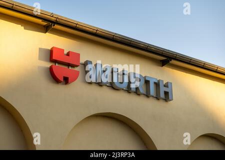 Logo der Würth-Gruppe an der Fassade eines Geschäftsgebäudes. Das Unternehmen ist bekannt für Montage- und Befestigungsmaterialien. Das Schild führt zum Einzelhandelsgeschäft. Stockfoto