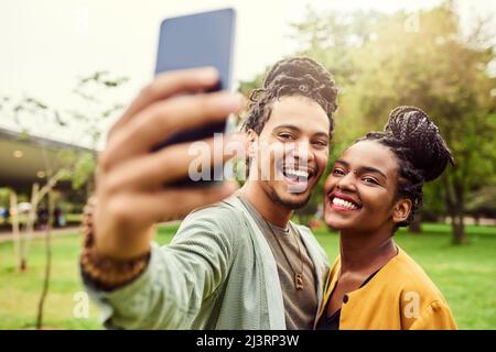 Selfies im Park mit meinem Schatz. Eine kleine Aufnahme eines jungen, schönen Paares, das den Tag in einem öffentlichen Park verbringt. Stockfoto
