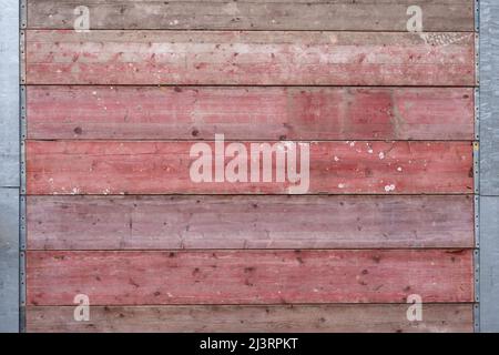 Holzplanken Textur auf einer Baustelle außen. Die Bretter, die zu einer rot gefärbten Wand zusammengefügt wurden. Verschmutzte raue Oberfläche des Materials. Stockfoto