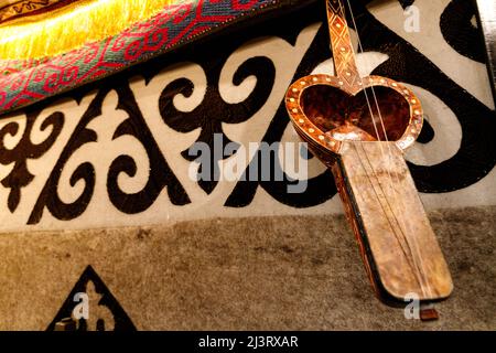 Kobyz, kasakisches Nationalmusiker-Instrument, auf dem Hintergrund eines Teppichs mit kasakischem Ornament, Kopierraum. Stockfoto