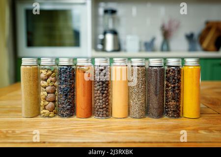 Verschiedene Gewürze in Glaskolben für Gewürze auf dem Tisch in der heimischen Küche mit Kopierplatz. Stockfoto