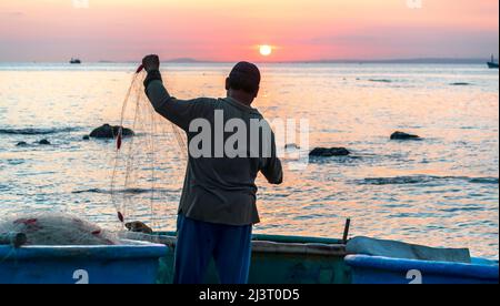 Blick auf den Strand am Korbbootdock bei Sonnenuntergang, während sich die Fischer an ihren Netzen darauf vorbereiten, am nächsten Morgen in Mui Ne, Vietnam, die Segel zu setzen Stockfoto
