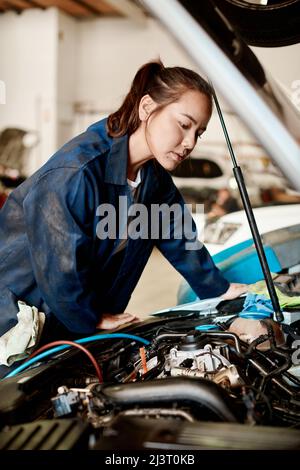 Es ist meine Aufgabe, schwierige Probleme zu lösen. Aufnahme einer Mechanikerin, die in einer Autowerkstatt an einem Auto arbeitet. Stockfoto