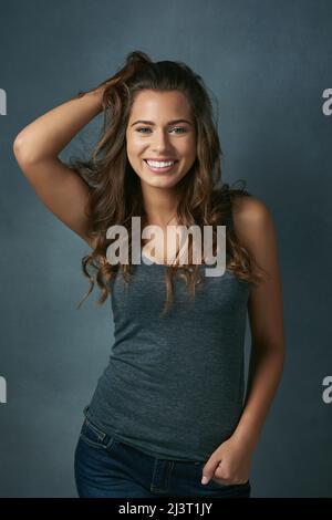 Unordentliche Haare sind egal. Studioaufnahme einer schönen jungen Frau, die vor blauem Hintergrund posiert. Stockfoto