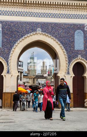 Fes, Marokko.  Bab Boujeloud, Eingang zum Fes El-Bali, der alten Stadt.  Frau in moderner Tracht, Mann in Levis und westliche Kleidung. Stockfoto