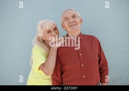 Glückliche ältere Frau und Mann stehen zusammen und posieren für die Kamera auf hellgrauem Hintergrund Stockfoto