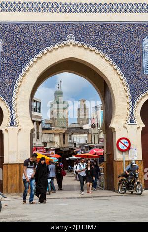 Fes, Marokko.  Bab Boujeloud, Eingang zum Fes El-Bali, der alten Stadt.  Frau in konservativen schwarze Djellaba begleitet von Mann in Levis und Western-sty Stockfoto