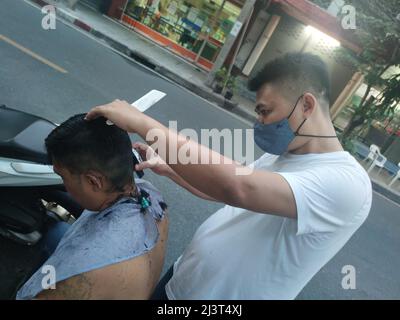 Bangkok, Thailand - Januar 22. 2022: Street Barber Haircuting a man using Hair Clipper Stockfoto