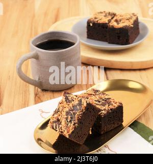 Backen Sie Brownie mit geschreddertem Käse auf der Oberseite oder Brownies Keju, hausgemachten frisch gebackenen Schokoladenkuchen auf dem Holztisch. Nahaufnahme. Stockfoto