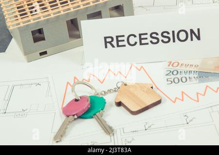 Schlüssel des Hauses, Währungen Euro, Abwärtsgraphen und Inschrift Rezession auf elektrischen Baudiagrammen. Immobilienkrise Stockfoto