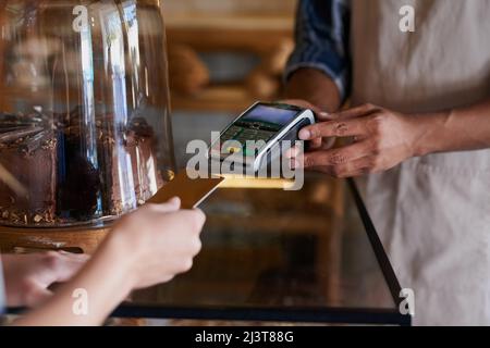 Lege es über mein Scheckkonto. Nahaufnahme eines Kunden, der eine Kreditkartenzahlung in einem Café abgibt. Stockfoto