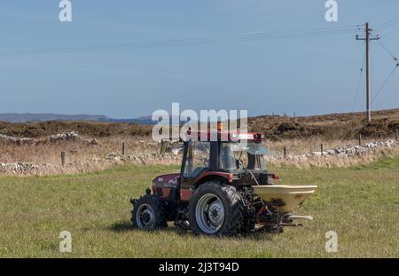 Crookhaven, Cork, Irland. 09.. April 2022. Bauer Edward Burchill mit seinem Hund Rexie verteilt Dünger auf Ackerland außerhalb von Crookhaven, Co. Cork, Irland. - Bild David Creedon Stockfoto