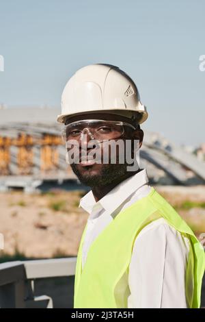Porträt eines jungen männlichen Ingenieurs, der auf der Baustelle posiert Stockfoto