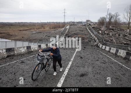 Borodyanka, Ukraine. 06. April 2022. Eine Frau mit einem Fahrrad überquert eine gesprengte Brücke am Eingang zu Borodianka als Folge des Angriffs russischer Eindringlinge. Borodyanka, die Anfang März von russischen Truppen eingenommen wurde, wurde einen Monat später aus der ukrainischen Armee entlassen. Es ist noch nicht bekannt, wie viele Menschen in diesem Dorf während dieser Zeit starben, aber nach früheren Aussagen der ukrainischen Behörden erlitt es die größte Zerstörung aller Siedlungen in den Vororten der Hauptstadt. Kredit: SOPA Images Limited/Alamy Live Nachrichten Stockfoto