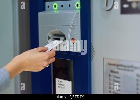 Bezahlen oder bleiben. Zugeschnittene Aufnahme einer nicht erkennbaren Person, die ein Ticket in einen Zähler einführt. Stockfoto