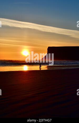 Atemberaubende Aufnahme eines wunderschönen Sonnenaufgangs in Saltburn-by-the-Sea an der Küste von North Yorkshire, Großbritannien. Auch ein Hundespaziergänger am frühen Morgen genießt die Szene. Stockfoto