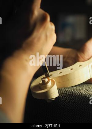 Handwerkliche Bildhauerei einer Geigenrolle - Konzept des Geigenbauers bei der Arbeit Stockfoto