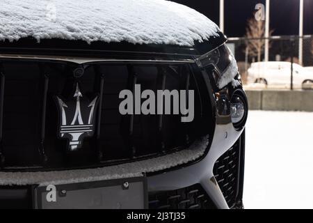 Das Emblem-Logo von Maserati, einem italienischen Hersteller von Luxusfahrzeugen, ist auf dem Kühlergrill eines neuen Autos zu sehen, das bei einem Autohaus geparkt ist. Stockfoto