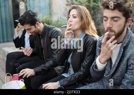 Schlechte Gewohnheiten - Gruppe von jungen Freunden rauchen Zigaretten zusammen im Freien. Ungesunde sucht Konzept. Stockfoto