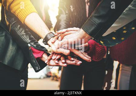 Gruppe von Menschen, die sich in Stapel zusammenschließen - Konzept der Begegnung verschiedener Studenten aus verschiedenen Rassen, die eine Einigung haben - keine Gesichter Stockfoto