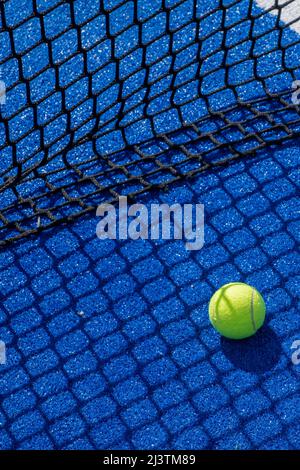 Paddel-Tennisball im Schatten des Netzes eines blauen Paddel-Tennisplatzes, Schlägersportkonzept Stockfoto