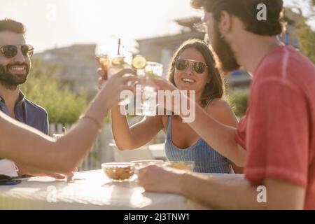 Junge Leute toasten mit Mojitos-Cocktails zur Happy Hour Stockfoto