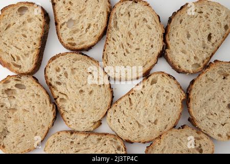 Draufsicht auf leckere Vollkornbrotscheiben auf weißem Hintergrund, frisches rustikales Brot mit Zwiebeln Stockfoto