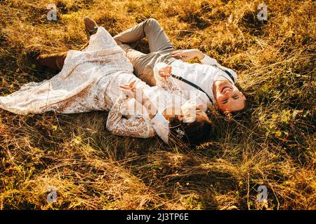 Glückliches junges Paar, das im Herbst auf dem Gras liegt. Romantische Lage Stockfoto