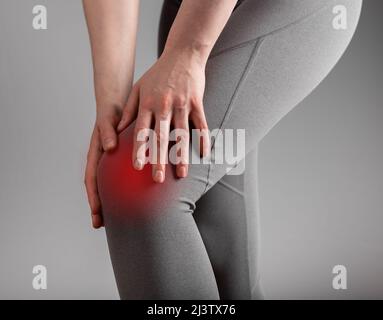 Knieschmerzen. Frau mit schmerzhaftem Bein und Nahaufnahme eines roten Punktes. Arthritis, Sehnenentzündungen, verstauchte oder angespannte Bänder folgen. Gesundheitswesen, orthopädische Probleme und Medizin Konzept. Foto Stockfoto