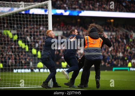 Ein Eindringling/Protest auf dem Spielfeld wird von Stewards und Mitarbeitern gestoppt - Tottenham Hotspur gegen West Ham United, Premier League, Tottenham Hotspur Stadium, London, Großbritannien - 20.. März 2022 nur zur redaktionellen Verwendung - es gelten die DataCo-Einschränkungen Stockfoto