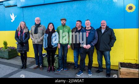 Starbeck, Harrogate, Großbritannien. 10. April 2022. Mitglieder der Starbeck Community Group Jill De Witt, Andrew Hart, Lucky Hubbard, Nik Mills, John Keane, David Stead und Colin Wilson fotografierten vor einer 40 Meter langen ukrainischen Flagge, die sie über dem einst schönen und heute verkommenen Harper-Gebäude in der Starbeck High Street gemalt hatten. Dies ist eines von vielen Projekten, an denen sie arbeiten, um ihre lokale Gemeinschaft zu beleben und zu motivieren. Kredit: ernesto rogata/Alamy Live Nachrichten Stockfoto