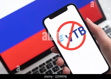 SPB, Russland - 8. April 2022: VTB-Bank und Sanktionen. Blockierte russische Bank, Logo und Ban-Symbol auf Handy-Bildschirm und Flagge Hintergrund Stockfoto